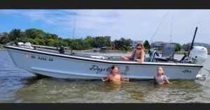 Boat on water with three people swimming.